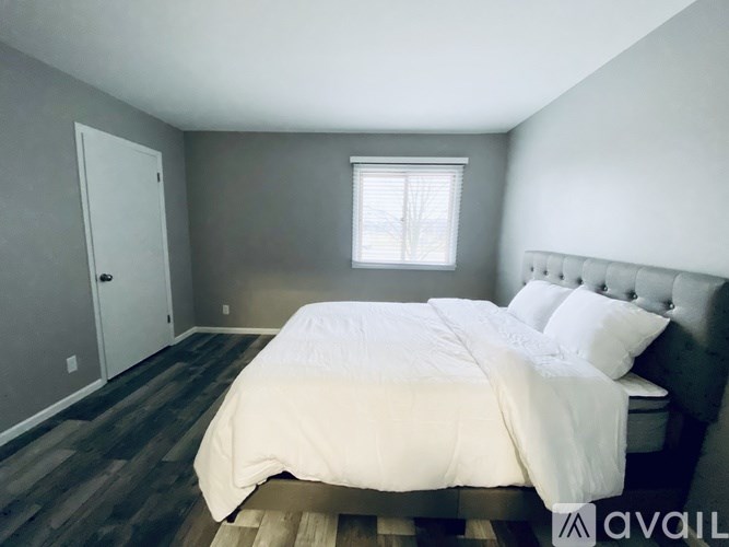 A bedroom with a bed, pillows, and a window.