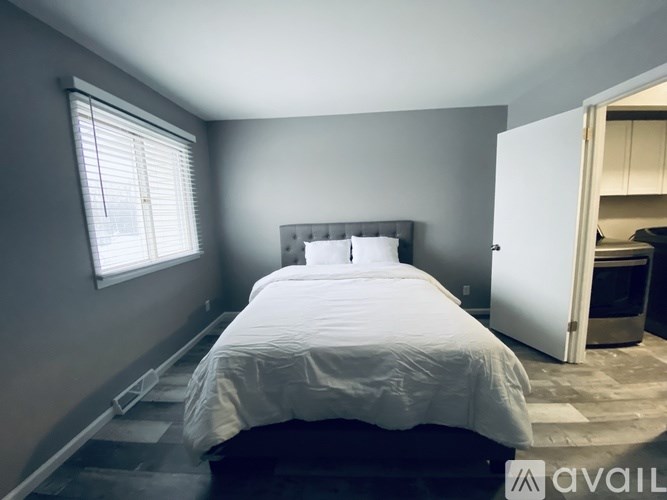 A bedroom with a bed, window, and a door leading to another room.