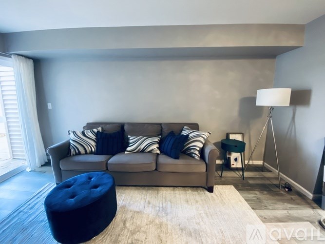 A living room with a grey couch and a blue ottoman.