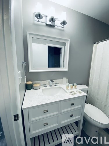 A bathroom with a white counter top and a mirror above it.