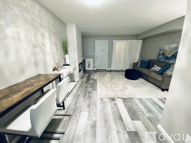 A modern living room with a wooden floor and white walls.