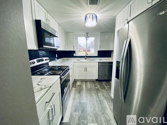A kitchen with a stainless steel refrigerator and a black stove top oven.