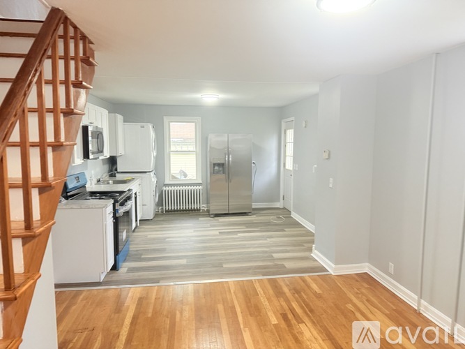 A kitchen with white appliances and a wooden staircase.