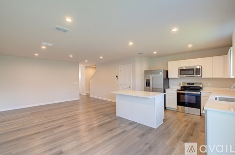 A kitchen with white cabinets and a wooden floor.