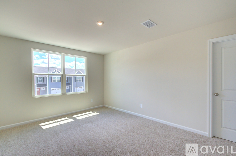 A room with a carpeted floor and a window showing a view of buildings outside.