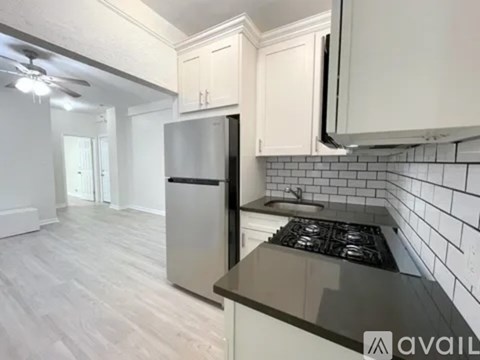 A kitchen with a stainless steel refrigerator and a black countertop.