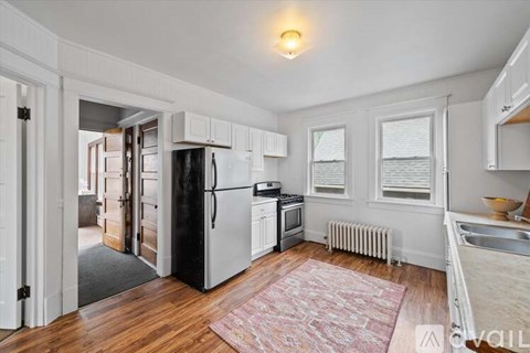 A kitchen with white cabinets and a black refrigerator.