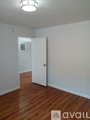 A room with a white door and wooden flooring.