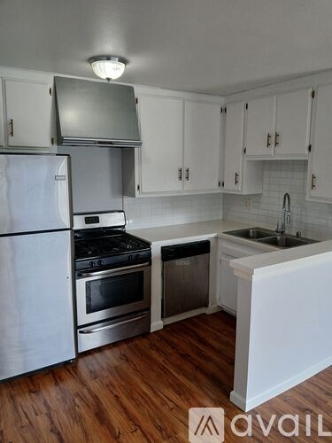 A kitchen with white cabinets and a wooden floor.