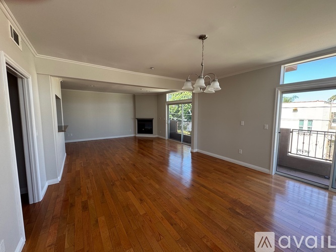 A spacious room with wooden floors and a large window.