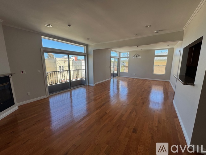 A spacious living room with hardwood floors and large windows.