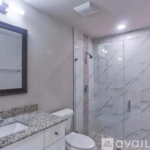 A bathroom with a marble counter top and a walk in shower.