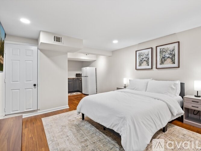 A bedroom with a large bed and two pictures on the wall.
