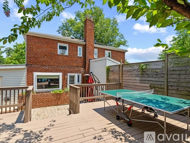 A red brick house with a green table tennis table in the backyard.