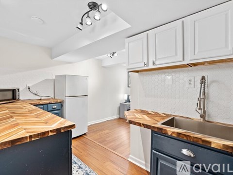 A kitchen with a wooden counter top and white cabinets.