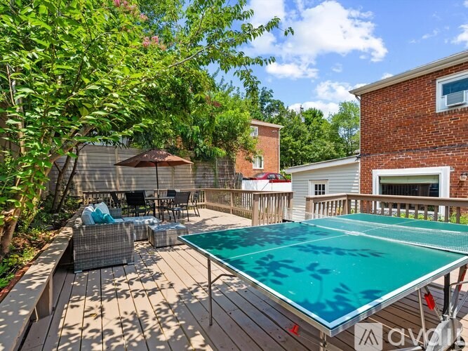 A pool table is surrounded by chairs and a table in a backyard.