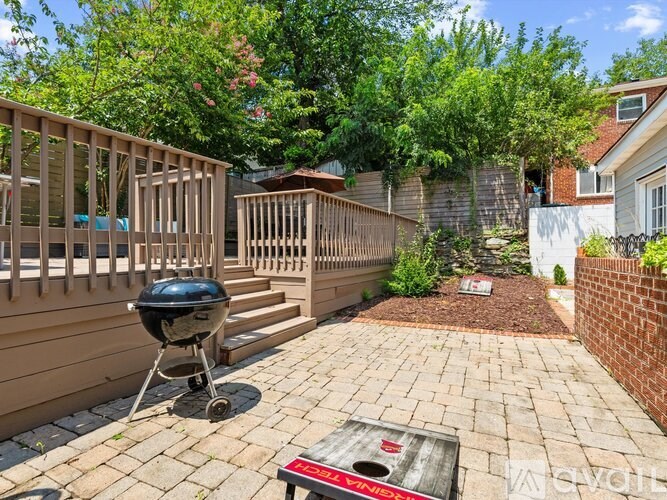 A backyard with a BBQ grill and a brick patio.