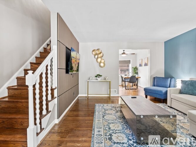 A living room with a blue couch and a wooden staircase.