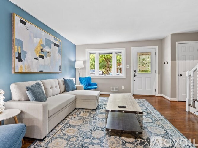 A living room with a white couch and a large painting on the wall.
