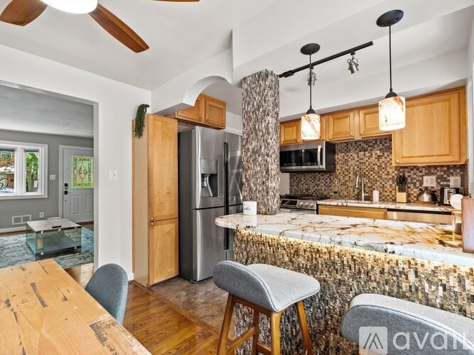 A kitchen with a refrigerator, microwave, and a counter with a stone backsplash.