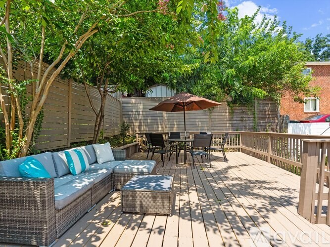 A patio with a couch, chairs, and an umbrella.