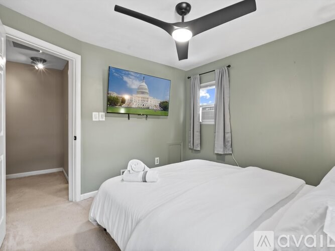 A bedroom with a bed, a ceiling fan, and a painting of the United States Capitol building on the wall.