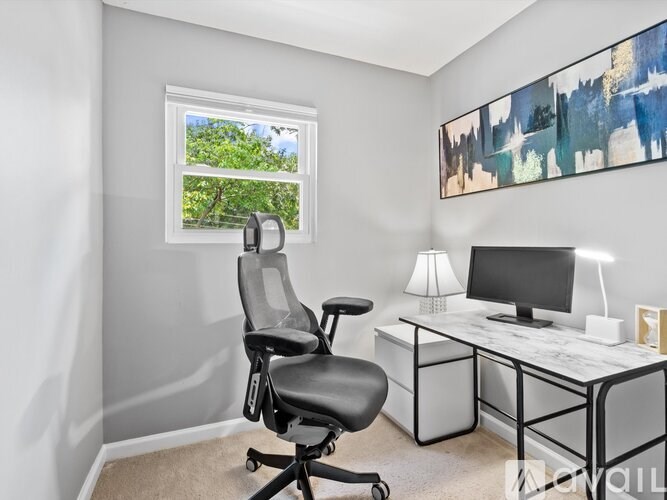 A room with a desk, chair, and a window showing greenery outside.