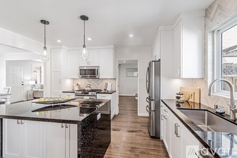 A modern kitchen with white cabinets and black countertops.
