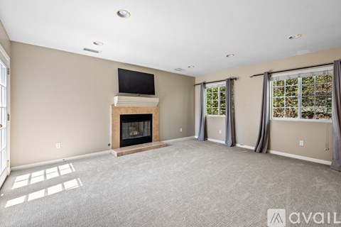 A living room with a fireplace and a television on top of a wooden stand.