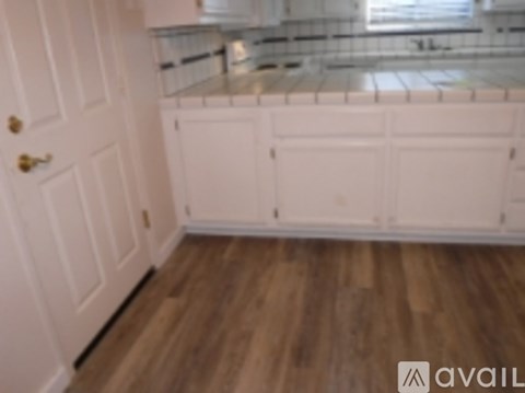 A kitchen with white cabinets and a wooden floor.