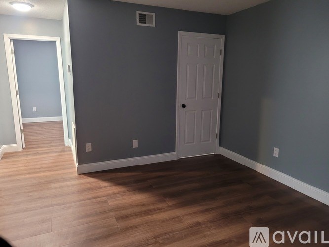 A room with a white door and a grey wall.