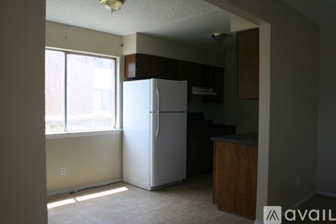 A kitchen with a white refrigerator and wooden cabinets.