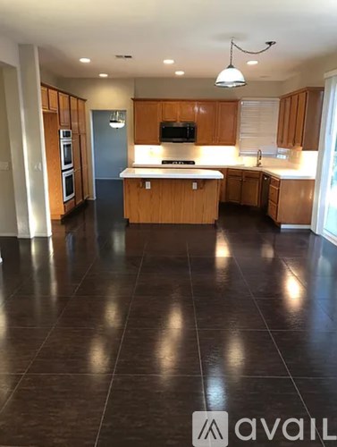 A kitchen with wooden cabinets and a black floor.