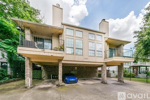 A modern house with a balcony and a car parked in front.