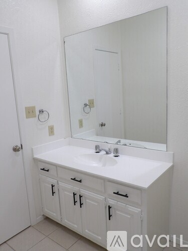 A white bathroom vanity with a sink and mirror.