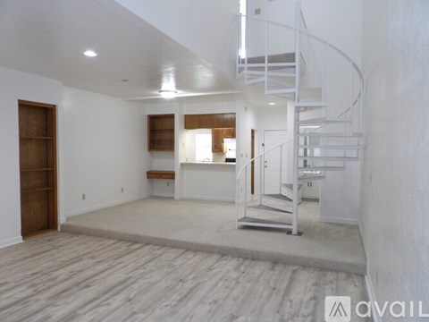 A spacious room with a spiral staircase and a wooden floor.
