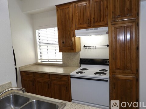 A kitchen with wooden cabinets and a white stove top oven.