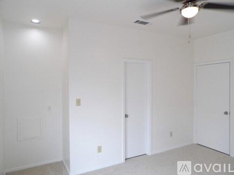 A room with a ceiling fan and three doors.