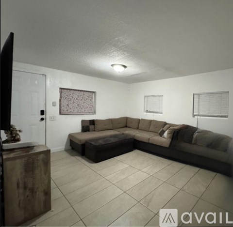 A living room with a brown couch and a wooden cabinet.