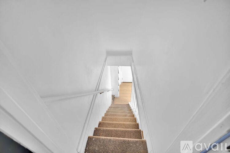 A staircase with a carpeted runner and white walls.