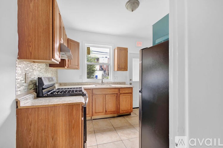A kitchen with wooden cabinets and a black refrigerator.