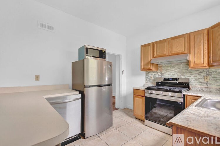 A kitchen with a refrigerator, oven, and sink.