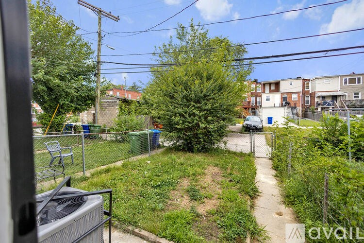 A backyard with a fence, a tree, and a utility pole.