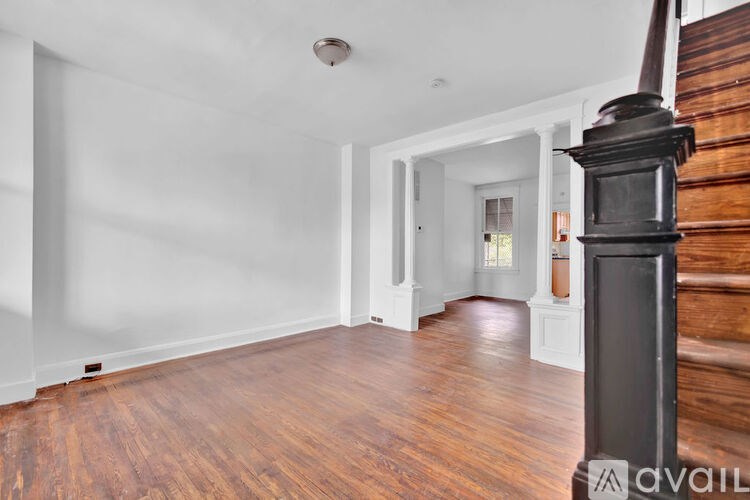 A room with wooden floors and a staircase on the right side.