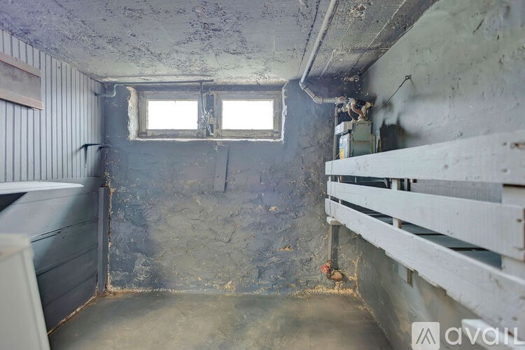 A room with a window and a wall that is peeling.