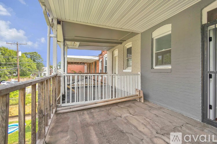 A porch with a railing and a view of a backyard.