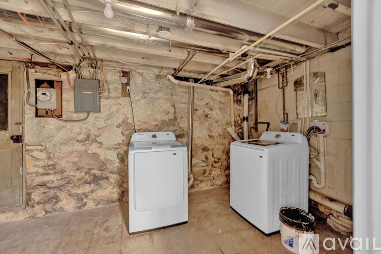 A room with two white washing machines and a wall made of stone.