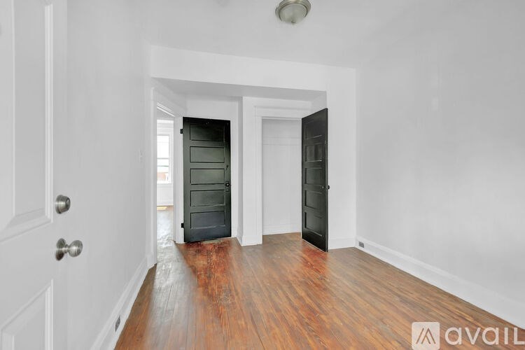 A room with a wooden floor and two doors, one of which is open.