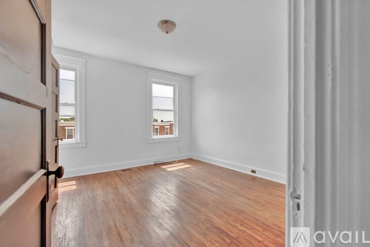 A room with wooden floors and two windows.