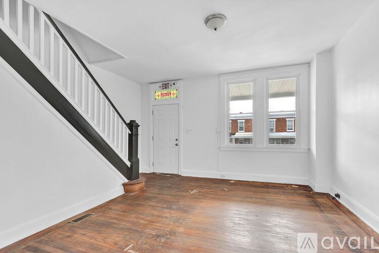 A room with a wooden floor and a staircase leading to the upper floor.